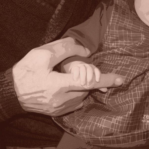 A closeup of a baby grasping the hand of the older person holding him. (Photo © FreeImages/Iwan Boin)